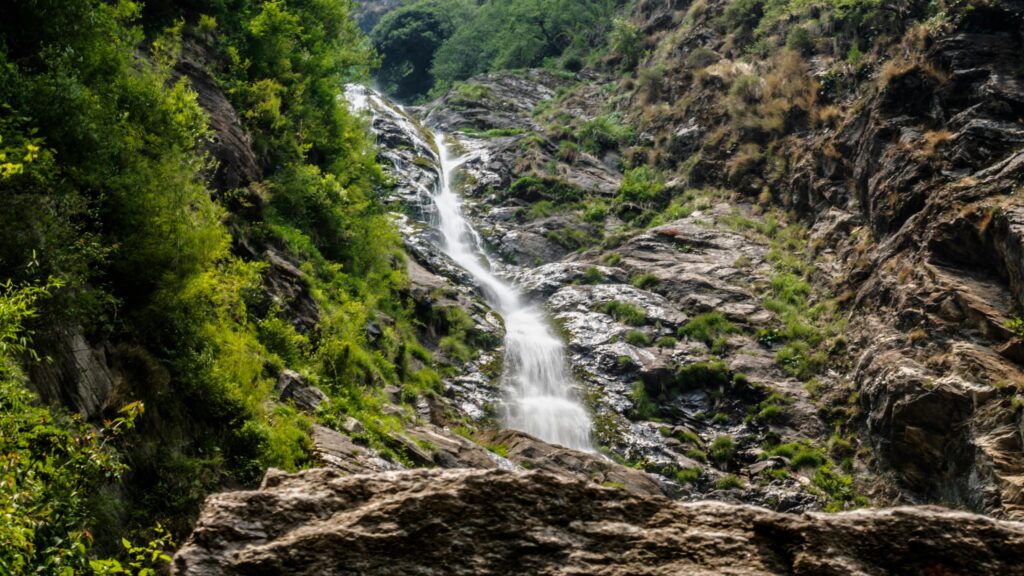 Explore the natural beauty of a cascading waterfall amidst lush greenery in Rambara, Uttarakhand.